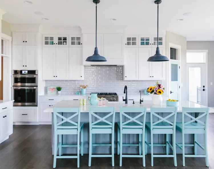 Белая кухня с островом и голубыми стульями