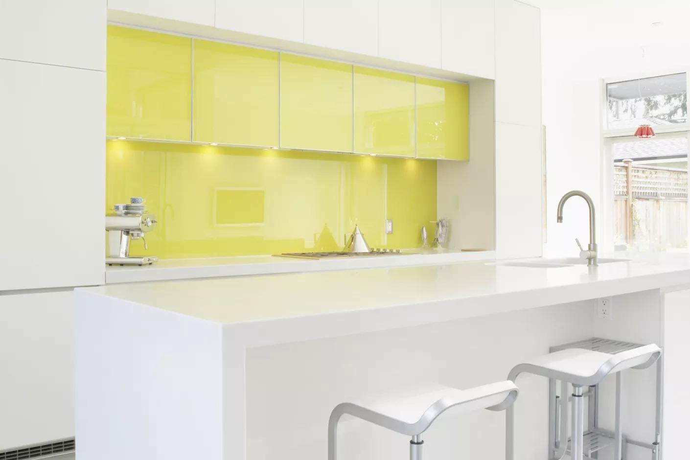 Белая кухня с ярким желтым фартуком и барной стойкой