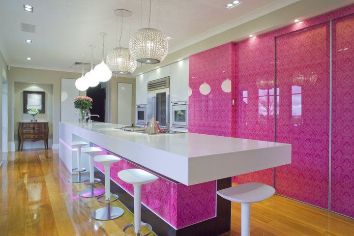 Ярко-розовый кухонный гарнитур в сочетании с белоснежным островом и табуретами