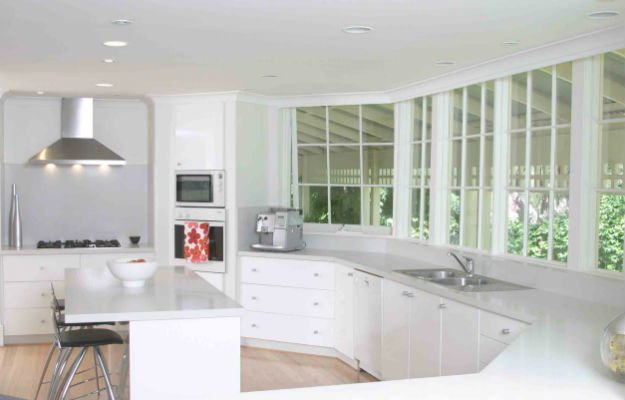 Панорамные окна с видом на сад в интерьере белой кухни