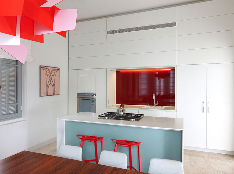 Коралловый цвет стены за мойкой в интерьере белой кухни