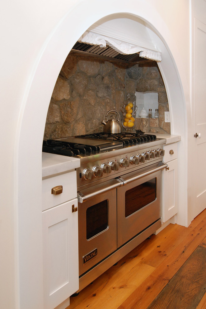 Кухонный фартук из натурального камня и современная бытовая техника в арочной нише кухни