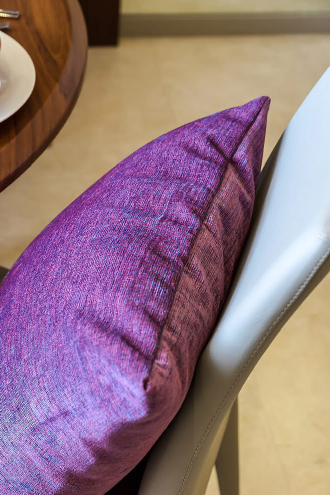 Фиолетовая декоративная подушка на голубом стуле