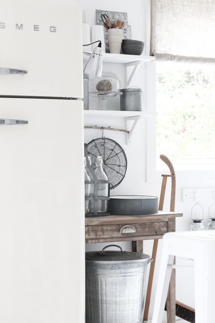 Белый холодильник SMEG на фоне деревянных белых кухонных полок